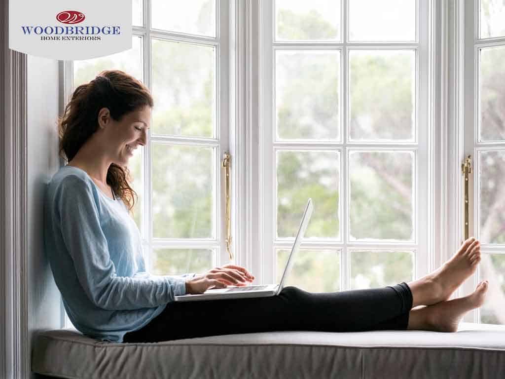 woman on laptop next to window