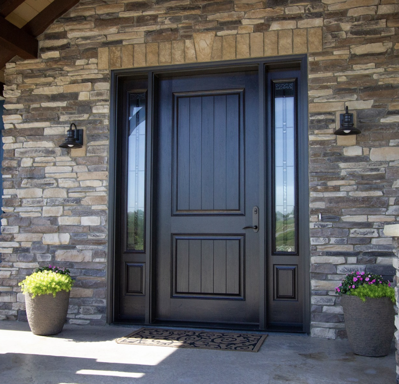 deep chocolate brown provia entry door with side-lights and bronze hardware surrounded by a nice and clean stone siding